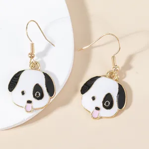 Detail of dog pendant earrings featuring white enamel and pink tongue with golden hooks