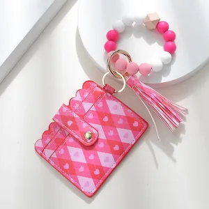Detail of pink silicone bead wristlet with heart print card holder and tassel keychain