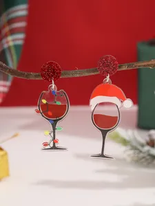 Detalle de pendientes navideños de acrílico con copa de vino y luces festivas