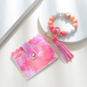 Close-up of pink floral PU leather wallet with silicone beaded bracelet and tassel