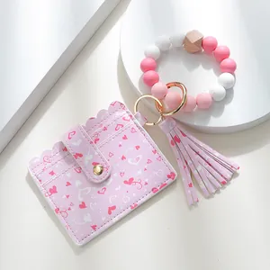 Detail of pink heart-printed PU card holder with silicone bead bracelet and tassel
