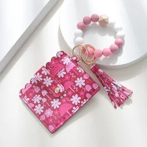 Close-up of pink floral leather card holder with silicone bead bracelet and tassel keychain
