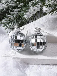 Detailed view of silver disco ball earrings with mirror tiles on festive pine branches
