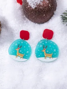 Close-up of Christmas earrings with reindeer and snowflake prints on acrylic drops