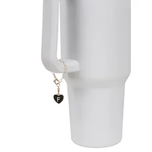 Detail of a golden heart charm with black enamel and letter F on a water bottle handle