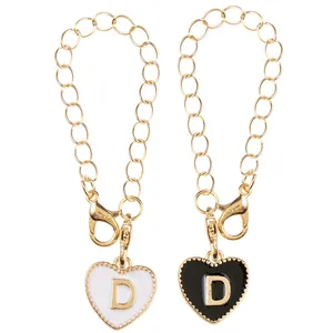 Close-up of black and white heart enamel alphabet D pendants with golden chain links
