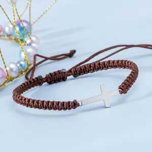 Dettaglio del bracciale intrecciato marrone regolabile con pendente a croce argento