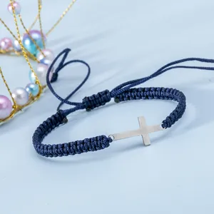 Dettaglio macro del bracciale a cordoncino blu scuro intrecciato a mano con croce d'argento
