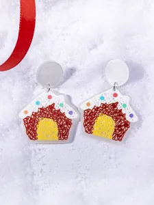 Detail of gingerbread house acrylic earrings with colorful candy dots and snow backdrop