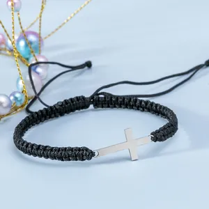 Dettaglio del bracciale a corda nera intrecciata con ciondolo a croce in metallo argento