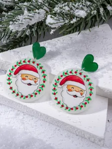 Macro detail of Christmas Santa Claus acrylic drop earrings on a snowy stone display