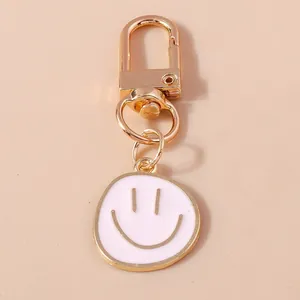 Cartoon smiley face keychain pendant with gold plating and white enamel charm
