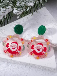 Detail of Christmas earrings featuring Santa Claus and floral acrylic pendants on a pine branch