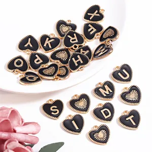 Detailopname van zwarte emaille hartbedeltjes met gouden letters voor DIY-sieraden