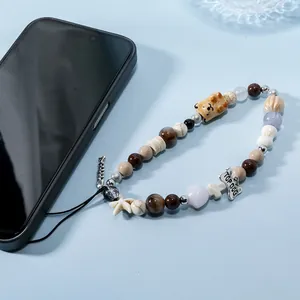 Handmade beaded phone charm with fishbone, dog charm, and earthy tone ceramic beads