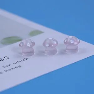 Détail macro de trois mini champignons en résine rose à pois blancs sur fond bleu