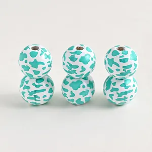 Detail of wooden farm beads with teal cow print pattern for DIY jewelry crafts