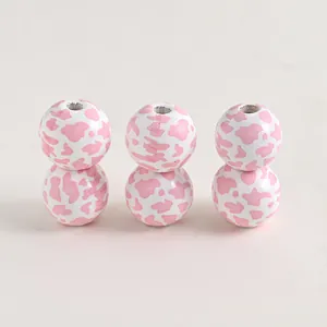 Close-up of pink cow print round wooden beads for DIY farmhouse jewelry making