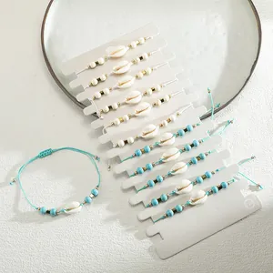 Set di 11 bracciali boho da spiaggia con conchiglie naturali e perline blu su cartoncino