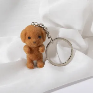 Brown flocked poodle teddy dog keychain with metal ring on a soft white fabric background