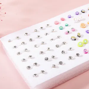 Detailed close-up of mixed fruit and rhinestone stud earring set on pink background