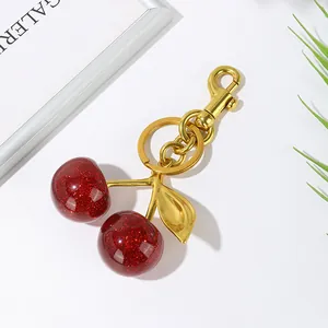Macro detail of red glitter cherry keychain with gold metal stem and lobster clasp