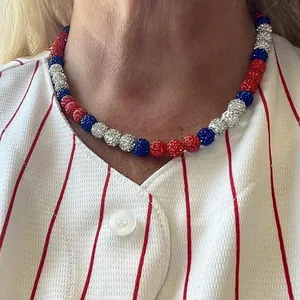 Détail d'un collier de perles en strass rouge blanc et bleu sur une chemise rayée