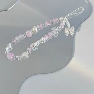 Détail d'une dragonne de téléphone avec perles roses et pendentif nœud blanc