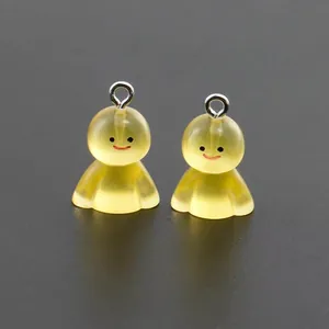 Close-up of two glowing yellow resin ghost charms with silver rings for DIY crafts