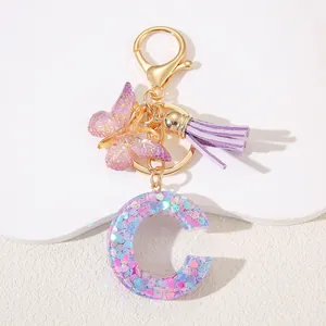 Macro view of purple resin letter C keychain with heart glitter and butterfly tassel