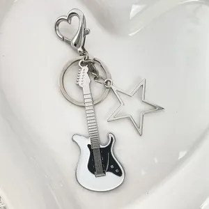 Dettaglio macro del portachiavi a chitarra d'argento con smalto su piatto a cuore bianco