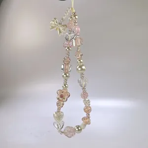 Détail de la dragonne de téléphone perlée avec papillons roses et perles crème