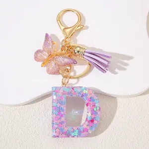 Detail of pink sequin resin letter D keychain with butterfly and tassel accessory