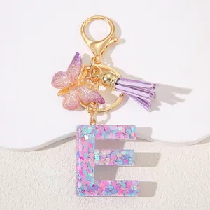 Detail of resin letter E keychain with pink sequins, purple tassel and butterfly charm