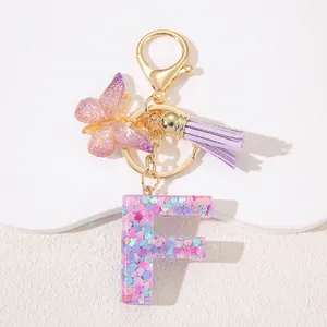 Detail of pink sequin resin letter F keychain with purple butterfly and tassel