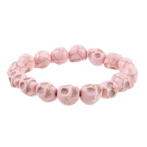 Close-up of pink gothic skull bead bracelet with natural stone texture on white background
