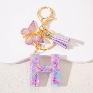 Detailed view of resin letter H keychain with pink heart sequins and purple tassel decor