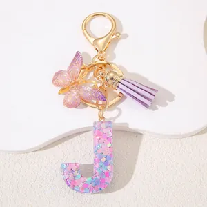 Macro shot of resin letter J keychain with pink heart glitter and purple tassel