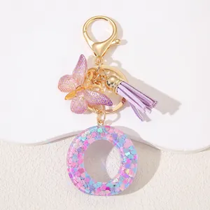 Detail of pink sequin resin letter O keychain with butterfly charm and purple tassel