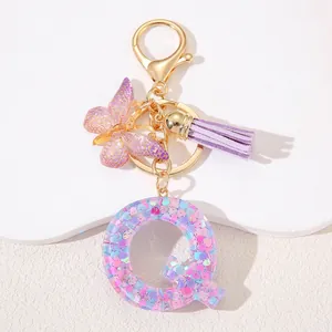 Detail of resin letter Q keychain with pink sequins, purple butterfly and suede tassel