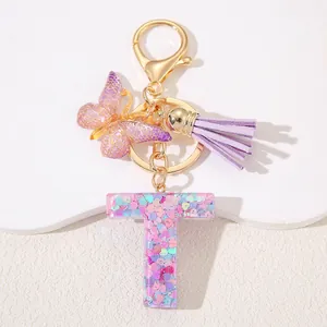 Detail of glitter resin letter T keychain with purple tassel and butterfly charm