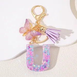 Detail of purple glitter letter U keychain with butterfly charm and purple tassel