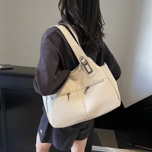 Detail van de grote crème tote bag met ritsvakken vooraan en een brede riem