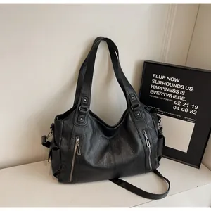 Detail of black faux leather tote bag with silver zippers and subtle pleated texture