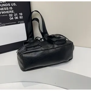 Detailed macro view of black faux leather texture and functional front pockets on tote bag
