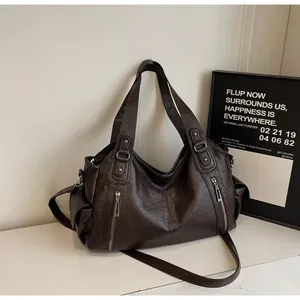 Detail of dark brown tote bag with silver zippers, rivets and lychee texture