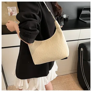 Detail der beigen Schultertasche mit Plissee-Struktur und verstellbarem Riemen am Model