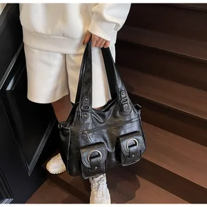 Detail of black vintage tote bag with large metal ring buckles and twin front flap pockets