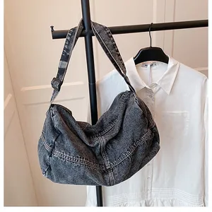 Macro shot of washed gray denim tote bag with white stitching and adjustable strap