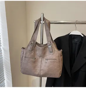 Detail van de taupe handtas met dubbele ritszakken en zilveren metalen decoratieve gespen